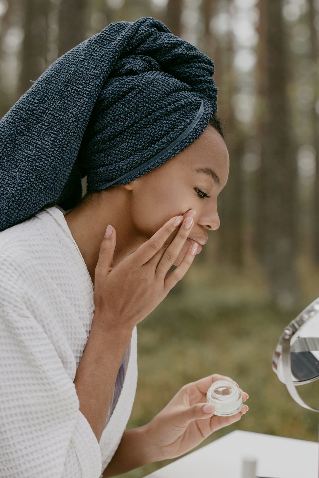 Black woman blending a cream into her cheek outdoors