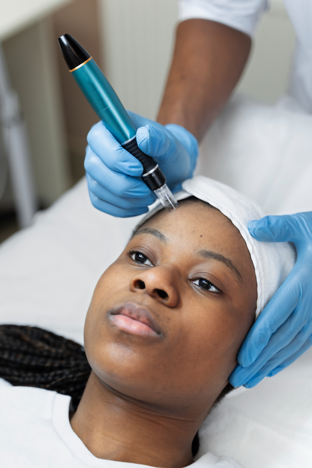 A person is receiving a RF Microneedling in Kampala at Refine Skin & Body Clinic, wearing a hair cover.